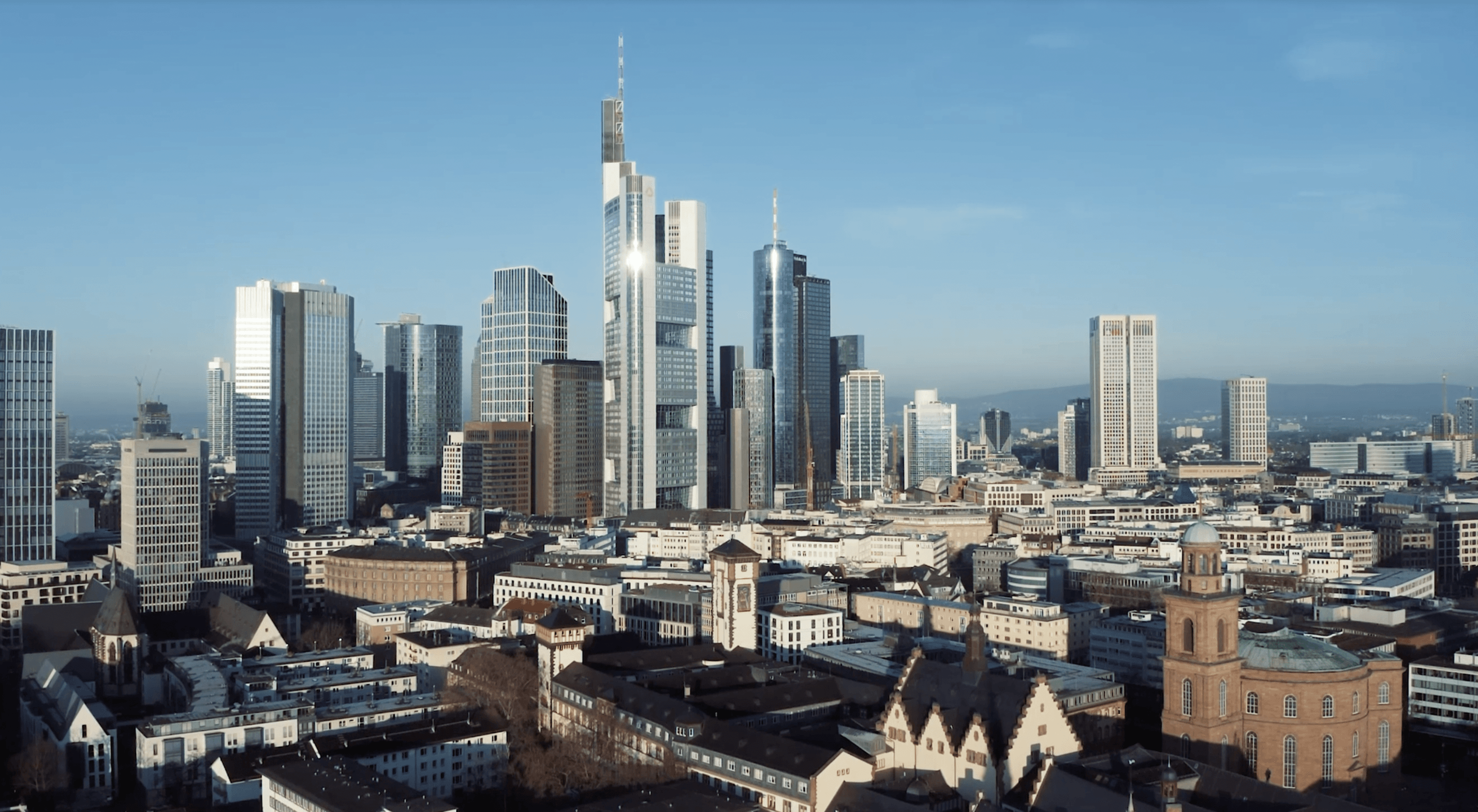 Die Frankfurter Skyline bei Sonnenschein und blauem Himmel.